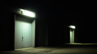Dimly lit garage doors illuminated by overhead lights in a serene night setting in Germany.