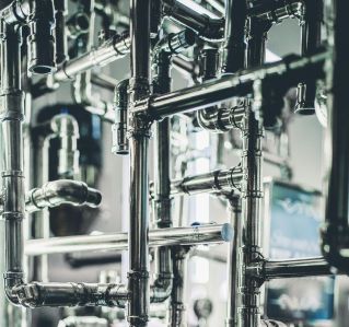 Close-up of complex stainless steel pipes in an industrial setting, showcasing modern engineering.