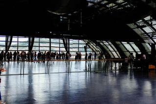Large indoor terminal with people reflected on glossy floors, emphasizes modern architecture.