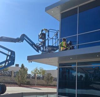 Desks with armchairs placed in spacious open space office with glass doors and white cupboards near big window in business center