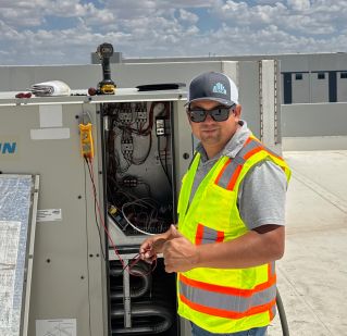 Two technicians repair a rooftop HVAC unit outside a Walmart store.