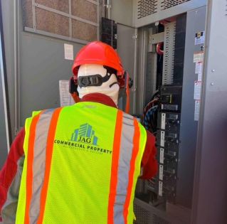 Hand of electrician working on a circuit breaker panel with colorful wires, ensuring safe electrical connections.